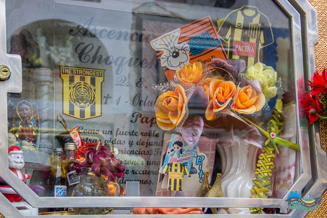 Garrafinhas de bebidas, flores e camisas do The Strongest (time de La Paz). Enfeites na Sepultura.